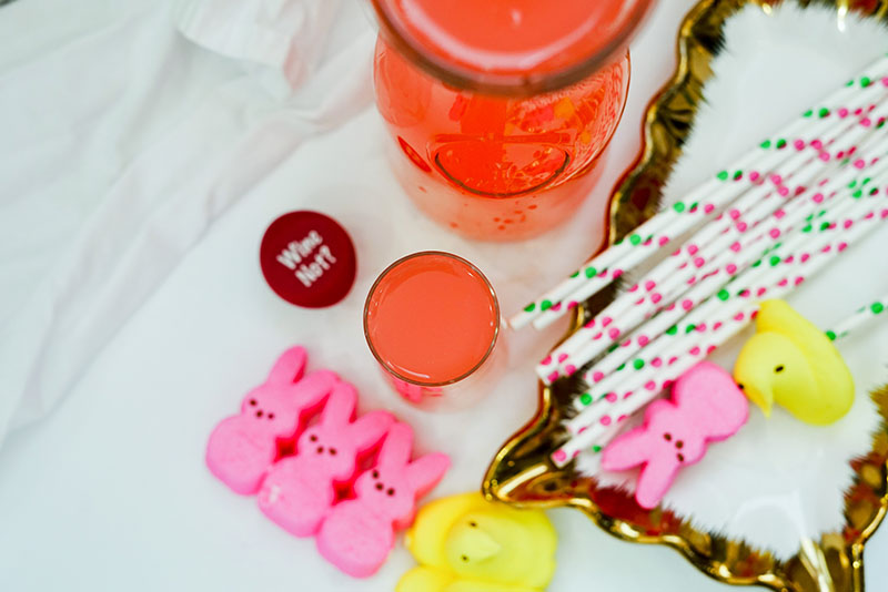 a birds eye view of a peeps mimosa cocktail next to pink and yellow peeps and easter themed straws